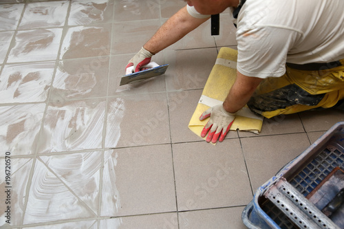 Grouting ceramic tiles on the floor by a man.