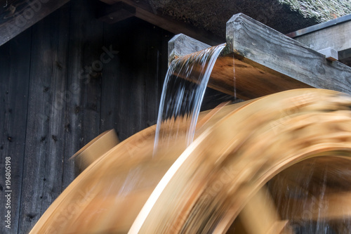 The part of mill wheel rotates under a stream of water, open air museum. The wooden trough brings water to the water mill wheel.