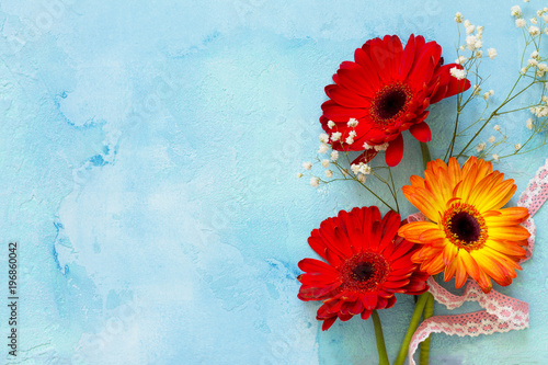 A wedding story or background Mother's Day. Three gerbera flowers on a stone background or slate with copy space. Copy space, top view flat lay background.