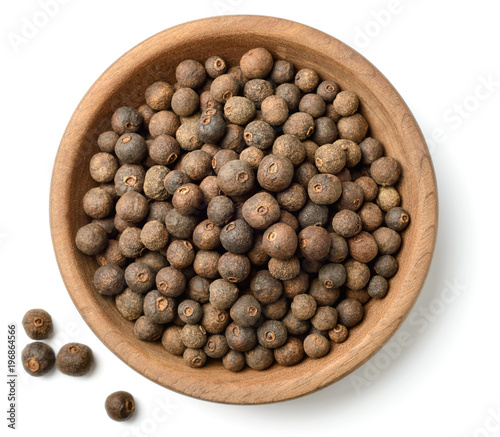 dried herb, allspice in the wooden plate. isolated on white, top view