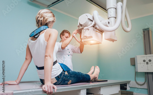 Radiologist and patient in a x-ray room. Classic ceiling-mounted x-ray system.