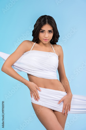 beautiful tanned girl in white chiffon, isolated on blue
