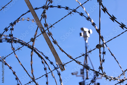 Barbed wire fence and surveillance cameras provide security - blue sky background with copy space