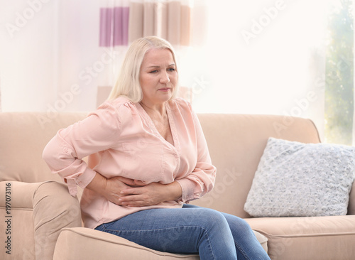 Mature woman suffering from stomach ache at home