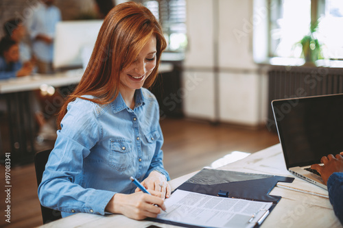 Young woman signing contract with manager