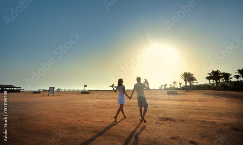 Happy young couple having beach fun on vacation honeymoon travel holidays. Caucasian woman and man playing playful enjoying love on date or honeymoon. Multiracial couple