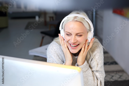 Kobieta z słuchawkami na uszach pracuje przy komputerze.