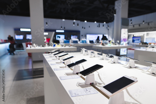 Many smartphones are on the table in the technology store. Buying a mobile phone at the electronics store. Smartphones on the background of the store