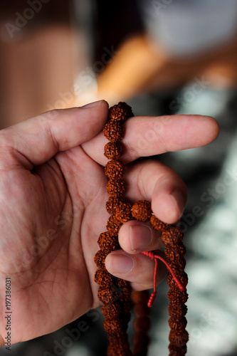 Hand of prayer holding rudraksha beads or rosary.