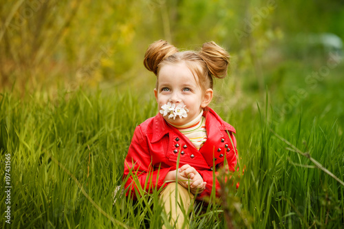 Little girl is sniffing flower in meadow