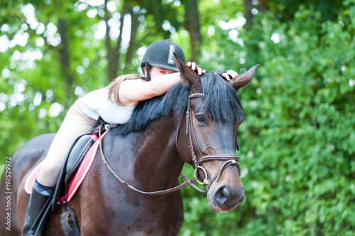 Young teenage girl-equestrian embracing her favorite frend-chestnut horse.