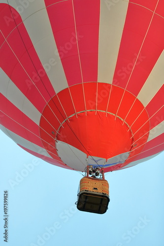 Kosz podpięty do kolorowego balonu, widok z dołu, w powietrzu, widoczna dolna część czaszy balonu