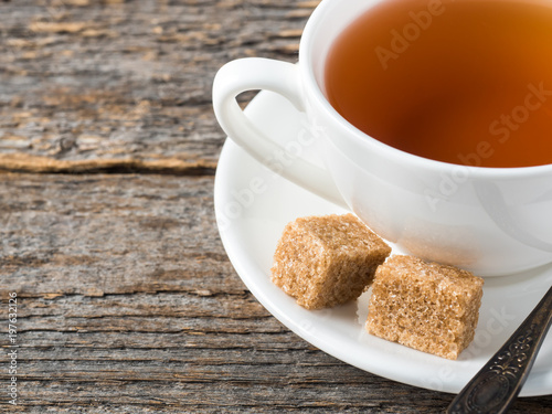 White tea Cup and saucer brown cane sugar on a rustic wooden background
