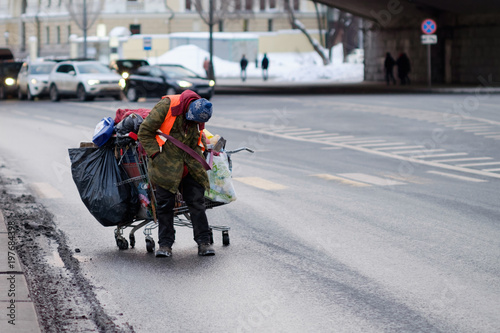 A tramp on the road, a cart with things