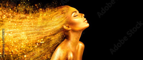 Kobieta moda model w złote jasne błyszczy. Dziewczyna z złotym skóry i włosy portreta zbliżeniem. Błyszczący wakacyjny profesjonalny makijaż na czarnym tle