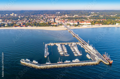 Sopot resort in Poland. Wooden pier (molo) with marina, yachts, pirate tourist ship, beach, vacation infrastructure, hotels, park and promenade. Aerial view at sunrise.