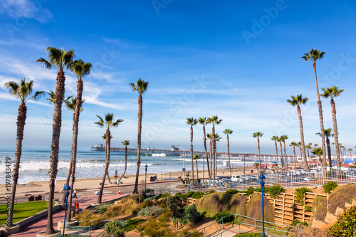 California Oceanside pier over the ocean with palm trees and beach, travel destination