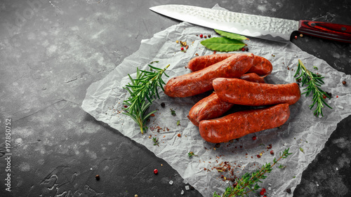 Freshly made raw breed butchers sausages in skins with herbs on crumpled paper.