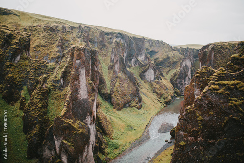 majestic rocky mountains with green vegetation and small river in fjadrargljufur, iceland