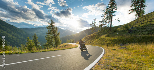 Motorcycle driver riding in Alpine highway, Nockalmstrasse, Austria, Europe.