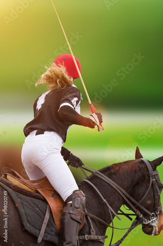 Polo woman player is riding on a horse.