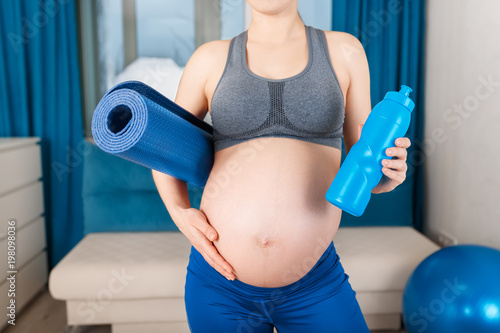 pregnant woman with with yoga mat