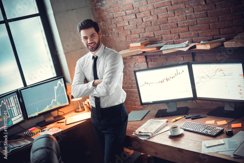 Young male trader at office work concept standing smiling confident