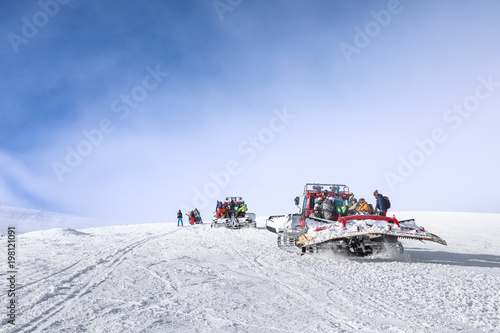 Tourists on ski piste at snowy resort. Winter vacation