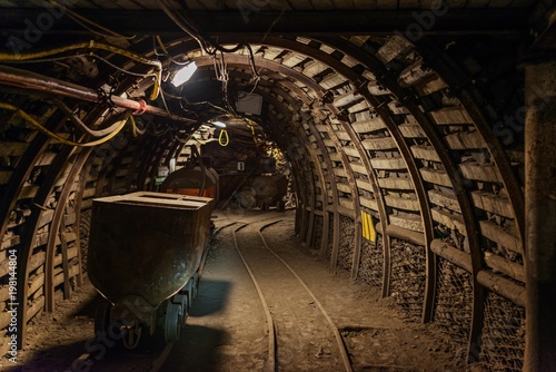 Underground train in black coal mine tunnel