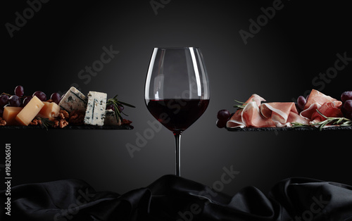 Kieliszek czerwonego wina z różnymi serami, owocami i szynką parmeńską.