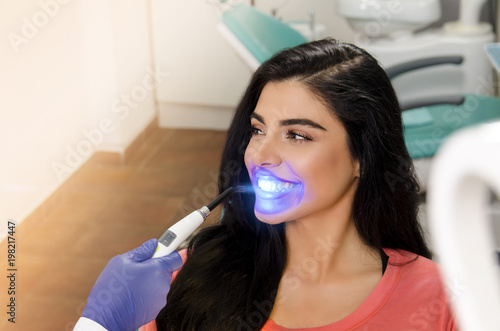 Gorgeous young woman UV lamp teeth whitening treatment 