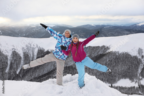 Happy couple having fun on snowy mountain peak at resort. Winter vacation