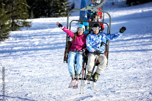 Happy couple on ski lift at snowy resort. Winter vacation