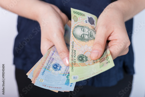 Photo of hands holding bundle of blue money in cash of Vietnamese dong as if being rich, boastful. Show off, pay bills or give bribe. Payment procedure