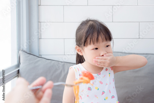 Little asian girl close her mouth by hand refuse to eat tomato in spaghetti