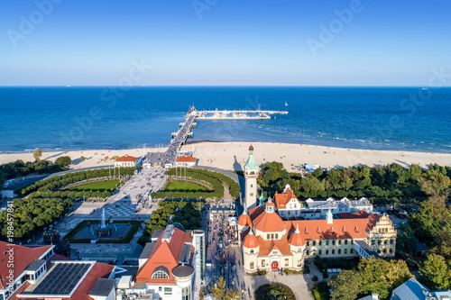 Sopot resort in Poland. SPA , old lighthouse, wooden pier (molo) with marina, yachts, beach, vacation infrastructure, park, promenade and walking people. Aerial view.
