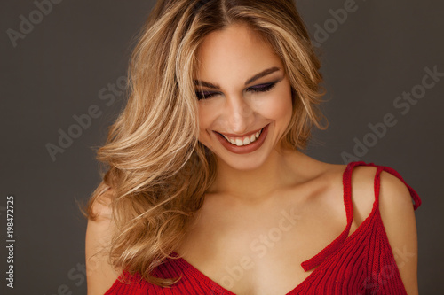 Gorgeous blonde woman portrait wearing red dress and smiling widely