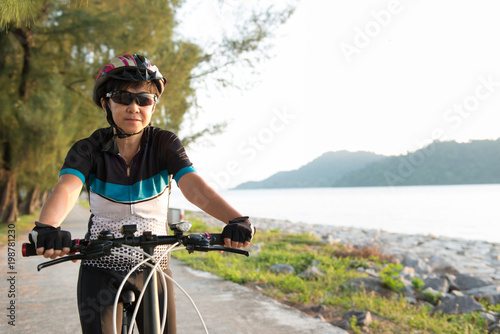 Joyful senior Asian woman riding a bicycle