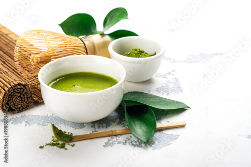 Green matcha tea drink and tea accessories on white background