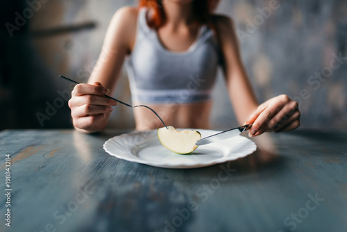 Female person against plate with a slice of apple