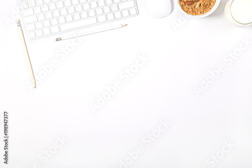 White modern keyboard, mouse, pencils, plate with granola and glass of milk on white background. Light minimal mockup. Concept of healthy lifestyle. Top view.