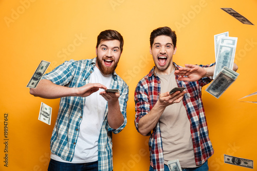 Portrait of a two happy young men scattering money
