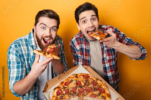 Portrait of a two hungry young men eating pizza