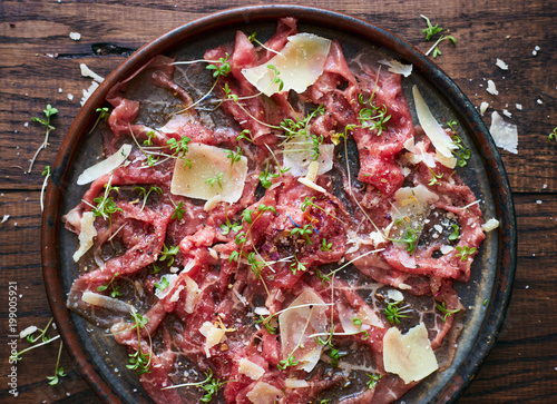 Delicious homemade beef carpaccio with Parmesan cheese spices and herbs top view