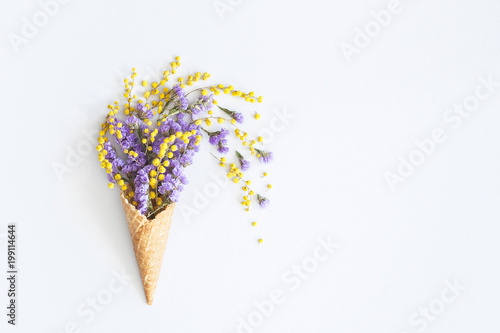 Flowers composition. Purple and yellow flowers in waffle cone. Flat lay, top view, copy space