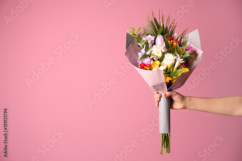 Woman with beautiful bouquet of freesia flowers on color background