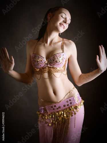 Exotic belly dancer woman with perfect body on a dark background.