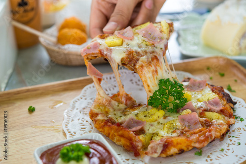 Tasty crispy oven-baked tortilla pepperoni pizza with spicy Italian sausage, melted cheese and tomato with a single slice being served in a restaurant, close up view