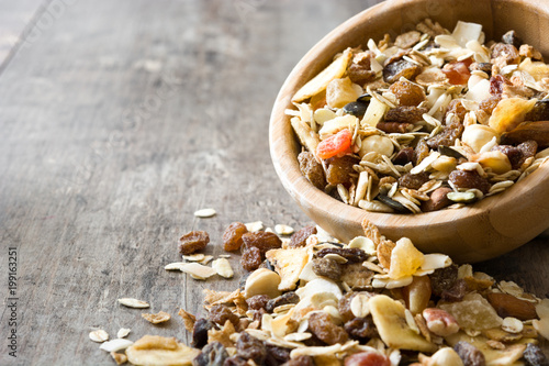 Muesli and dried fruit in wooden bowl on wooden table. Copyspace