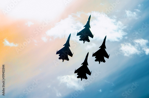 Group of four aircraft fighter jet airplane sun glow toned sky.
